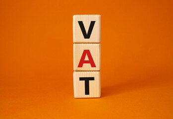 VAT - Value Added Tax symbol. Wooden cubes with word VAT. Beautiful orange background. Business and Value Added Tax concept. Copy space.