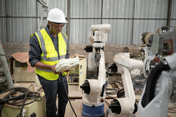 African American technician engineer man use remote control machine with checking and repair machine arm robot at factory	