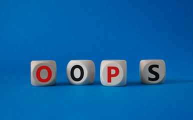 Oops symbol. Concept word Oops on wooden cubes. Beautiful blue background. Business and Oops concept. Copy space.