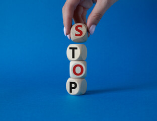 Stop symbol. Concept word Stop on wooden cubes. Businessman hand. Beautiful blue background....
