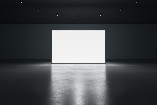 Front view of blank white glowing digital screen in dark hall interior with concrete floor and black wall. Presentation concept. Mockup, 3D Rendering
