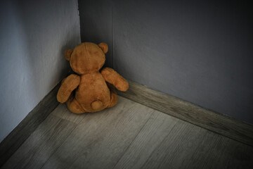Teddy bear soft toy sitting corner room.Concept of domestic violence against children.