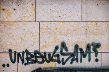 Wandschmiererei oder Graffito an einer Wand mit dem Schriftzug UNBEUGSAM.