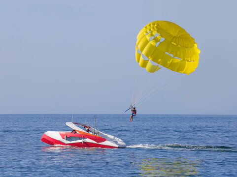 A yellow parasail wing pulled by a powerboat. Guy takes a selfie