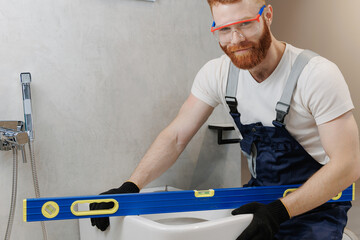Professional plumber working with toilet bowl in bathroom. Concept repair service plumbing. Portrait industrial man