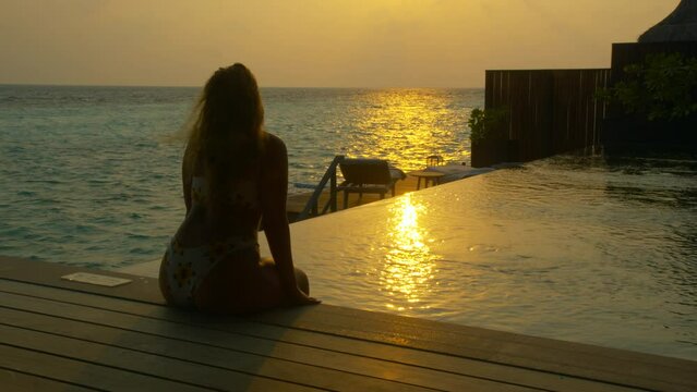 Woman watches sunset from luxury island resort villa