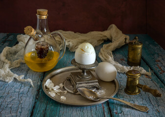 Obraz na płótnie Canvas Two white chicken eggs, an egg cup and a decanter with olive oil and vinegar. Breakfast.