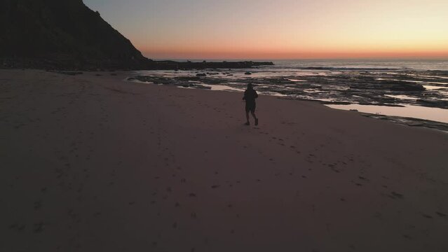 Man running training on the beach at sunrise in Australia.