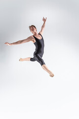 Fototapeta na wymiar Professional Ballet Dancer Young Caucasian Athletic Man in Black Suit Dancing in Studio On White Background