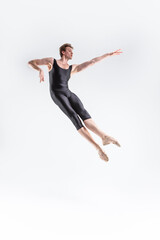 Fototapeta na wymiar Caucasian Ballet Dancer Young Caucasian Athletic Man in Black Suit Posing Flying Dancing in Studio On White.