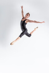 Fototapeta na wymiar Professional Ballet Dancer Young Caucasian Athletic Man in Black Suit Dancing in Studio On White Background With Lifted Hands.