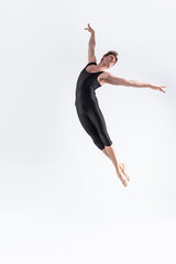 Fototapeta premium Ballet Dancer Young Man in Black Dance Suit Posing in Flying Ballanced Dance Pose Studio On White.