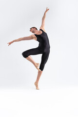 Fototapeta na wymiar male Ballet Dancer Young Athletic Man in Black Suit Posing in Ballanced Stretching Dance Pose Studio On White.