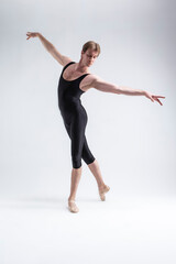 Fototapeta na wymiar Sports Concepts. Athletic Caucasian Dancing Ballet Man Posing in Stretching Pose With Hands Lifted in Line in Black Tights On White