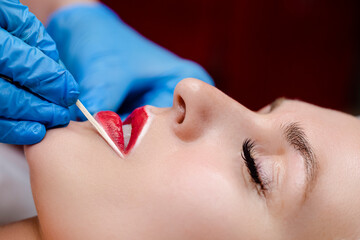 Permanent Tattoo Concepts. Young woman having permanent makeup on lips in beautician salon