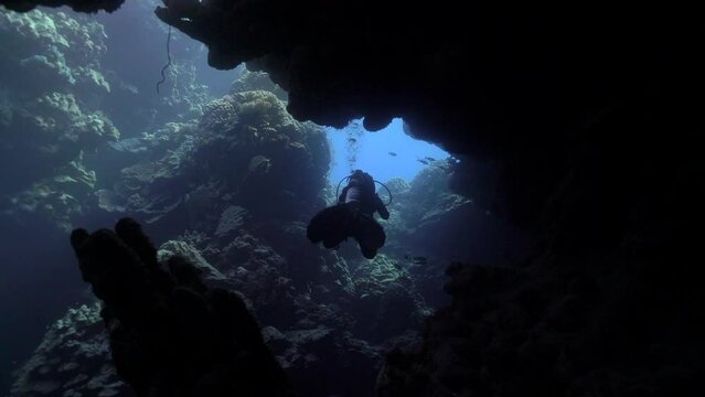 Under water film of swimming behind a scuba diver going trough an under water cave - Sail Rock island in Thailand