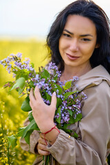 portrait of a brunette woman in a rapeseed field in spring