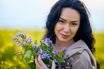 portrait of a brunette woman in a rapeseed field in spring