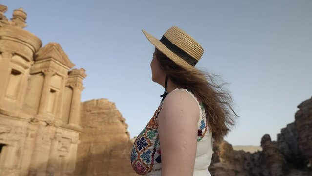 Tourist woman in straw hat enjoys Ad Deir Monastery in ancient Petra