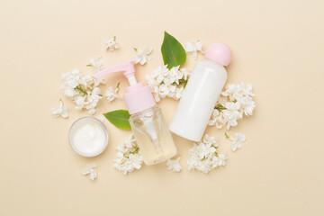 Composition with cosmetic bottles and flowers on color background, top view