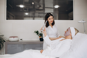 Woman applying mask on her face and looking in the mirror. woman applying natural facial mask.