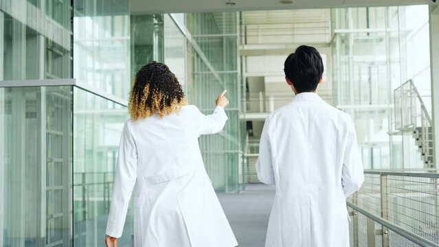 A multinational group wearing a white coat and walking through a facility.