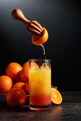 Tequila sunrise cocktail with ice and grenadine on a black background.