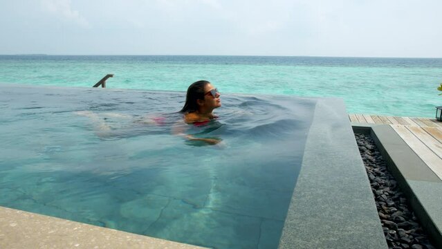 Woman swimming in luxury vacation ocean villa