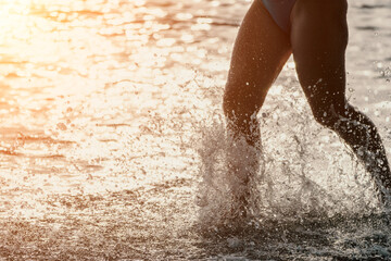 Running woman on a summer beach. A woman jogging on the beach at sunrise, with the soft light of the morning sun illuminating the sand and sea, evoking a sense of renewal, energy and health.