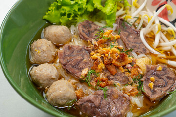 asian noodle soup with beef meatball with fresh vegetable on wood table vintage style, street food, hot and spicy noodle soup