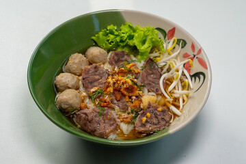 asian noodle soup with beef meatball with fresh vegetable on wood table vintage style, street food, hot and spicy noodle soup
