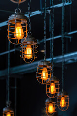 bright orange lamps in a dark ceiling. a burning electric light bulb screwed into the socket against a dark background