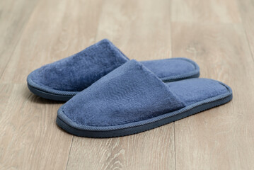 Pair of big blue slippers on the floor. Comfortable home shoes