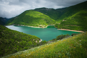 Beautiful scenery with the wide dam of Lago di Fiastra (Lake Fiastra) holding its glowing mirroring...