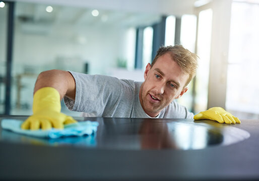 Man with gloves cleaning surface in office, health and hygiene in workplace, janitor at clean desk. Professional cleaner wiping table in workplace, maintenance and disinfectant on cloth for germs.