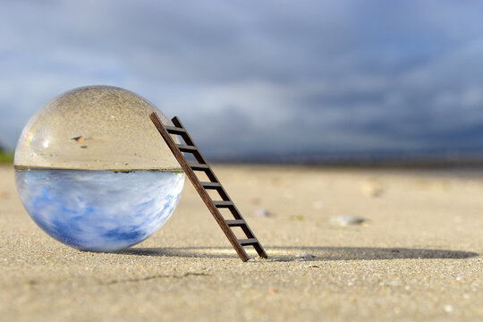 Close-up of crystal ball on sand at beach against sky