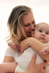 A loving grandmother gently hugs and kisses her granddaughter. Grandmother looks at her granddaughter. Family happiness. White background.
