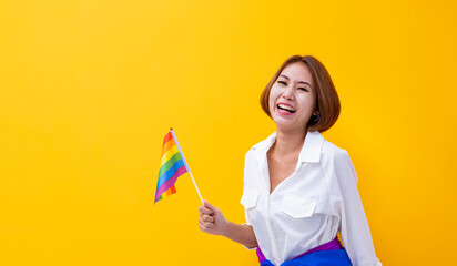 Portrait of Asian woman waving LGBTQ rainbow flag for coming out of the closet in pride month to...