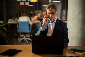 Businessman in office. Handsome man talking on phone at work..