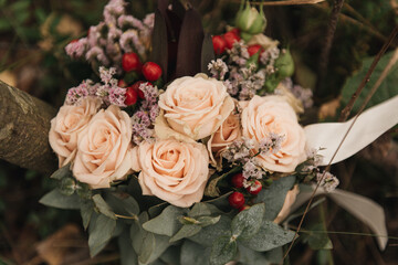 Beautiful wedding bouquet with protea and roses, wedding rings on a forest background
