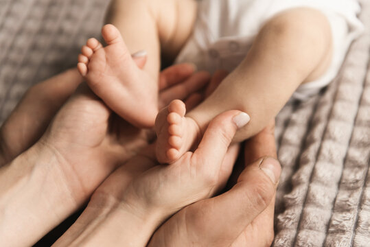 Baby's legs in the hands of mom and dad