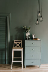 Modern interior in emerald color with decor candles, book, vase with flowers