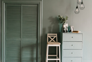 Modern interior in emerald color with decor candles, book, vase with flowers