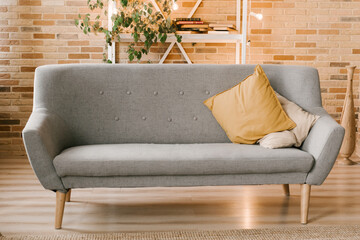 Modern interior design, gray sofa against a brick wall and a bookcase