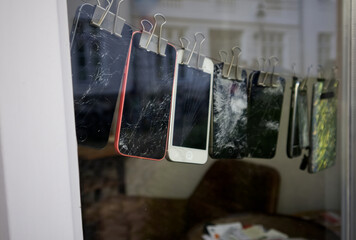 Mobile phones with a broken screen hanging on a rope attached with paper clips