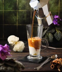 Cold coffee with ice cream in a glass goblet on a wooden background. Coffee recipes.