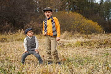 Naklejka na ściany i meble Two friends having fun in an autumn meadow. Kids having fun in the autumn park.