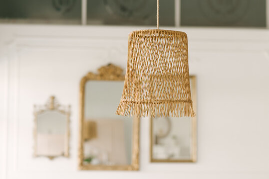 Beautiful hanging wicker lamp on the background of vintage mirrors