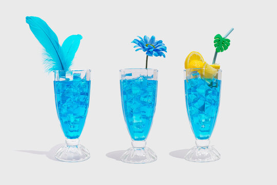 Alcohol juicy fruit blue cocktails with curacao liquor, lemon slice, ice cubes, feather, flower  and drinking straw. Summer drink, party scene. Trendy minimalist drink composition.