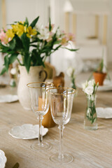 Dining table with beautiful setting, glasses and fresh flowers